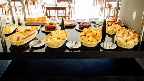 A buffet with various breads, pastries, and a cake. - Atrios Beach Hotel (Natal)