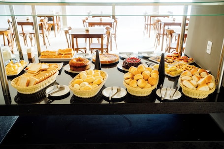 A buffet with various breads, pastries, and a cake.. Atrios Beach Hotel