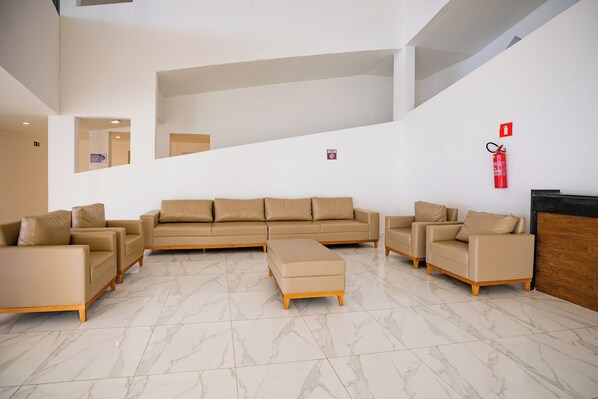 Un hall d’entrée moderne avec un grand canapé beige, un pouf assorti et une table basse en bois.