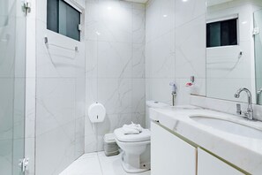 Een moderne badkamer met toilet, bidet en een grote spiegel.