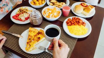 Uma mesa com diversos pratos, incluindo pizza, uma xícara de café e uma garrafa de água.