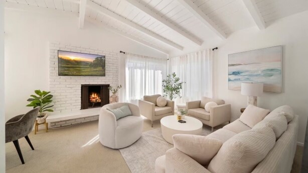 Una sala moderna con chimenea, muebles blancos y un ventanal grande.