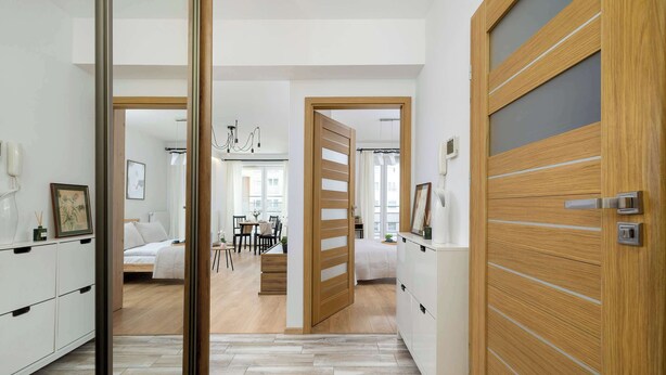 A modern hotel room with a wooden wardrobe, a bed, a desk, and a dining area. - Air-conditioned Apartment | Balcony, Parking and Workspace (Kraków)