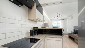 A modern kitchen with a black induction cooktop, wooden cabinets, and a built-in oven. - Air-conditioned Apartment | Balcony, Parking and Workspace (Kraków)
