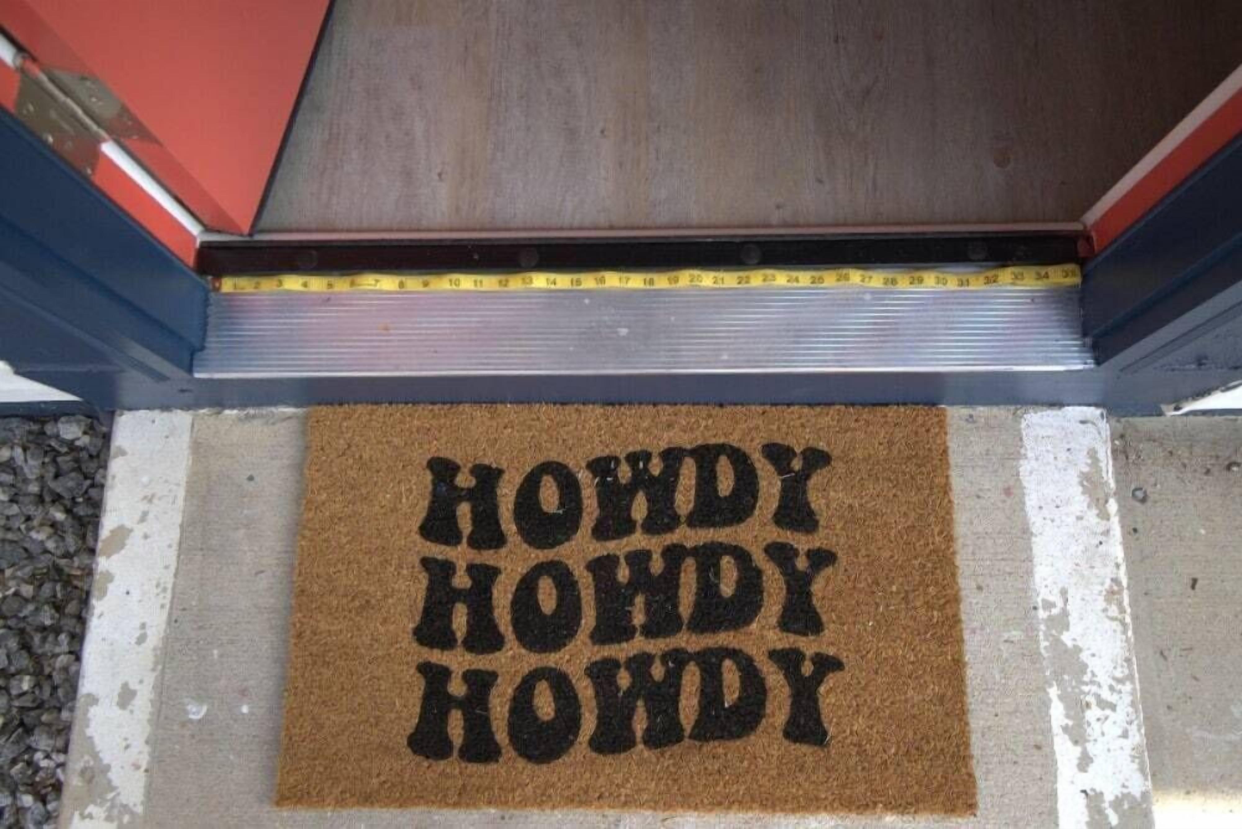 Een deurmat met de tekst 'HOWDY HOWDY HOWDY' op een bruine mat.