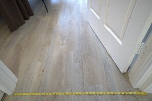 A wooden floor with a measuring tape indicating the room's dimensions.