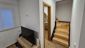 Et moderne værelse med et træskrivebord, et fladskærms-TV og en lille, hvid højttaler.