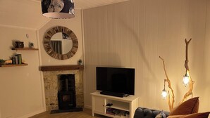 A living room with a fireplace, a television, a sofa, and a coffee table. - Braeburn (Bamburgh)
