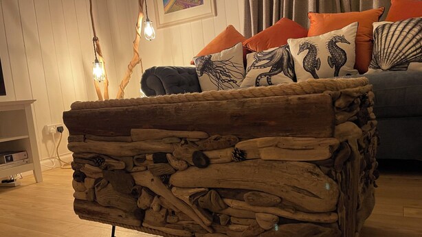 A rustic wooden coffee table with a natural finish, positioned in a living room with a sofa and decorative pillows. - Braeburn (Bamburgh)