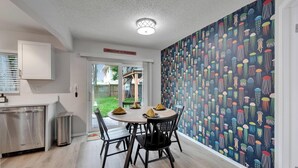 A modern kitchen with a dining area, featuring a patterned wall, a welcome sign, and a view of the outdoors. - Private Hot Tub - Close to Beaches - Fun Game Room (Clearwater)