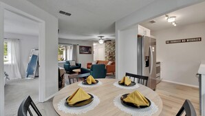 A dining area with a round table set for four, a ceiling fan, and a kitchen area with a refrigerator and cabinets. - Private Hot Tub - Close to Beaches - Fun Game Room (Clearwater)