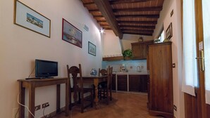 A compact kitchen with wooden cabinets, a dining table with chairs, and a television on a wooden stand. - Apartment in the heart of Tuscan nature. Pets allowed (Castelfranco Piandiscó)