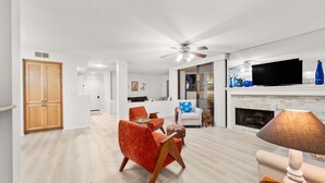 Un salón amplio con chimenea, ventilador de techo y televisor.