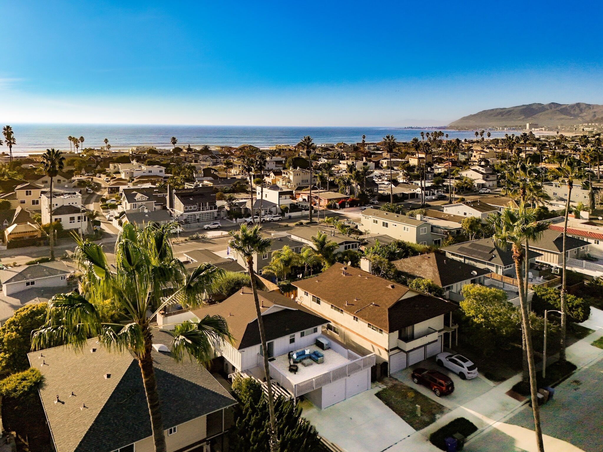 Um bairro residencial com casas, palmeiras e vista para o oceano.