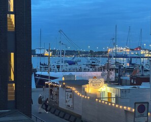 A marina at dusk with boats docked, a restaurant named 'Kulinarik Butze' with outdoor seating, and a 'No Parking' sign. - HarborEscape - Port of Travemünde (Lübeck)