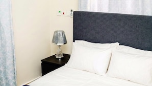 Een hotelkamer met een bed, nachtkastje, lamp en een stopcontact.