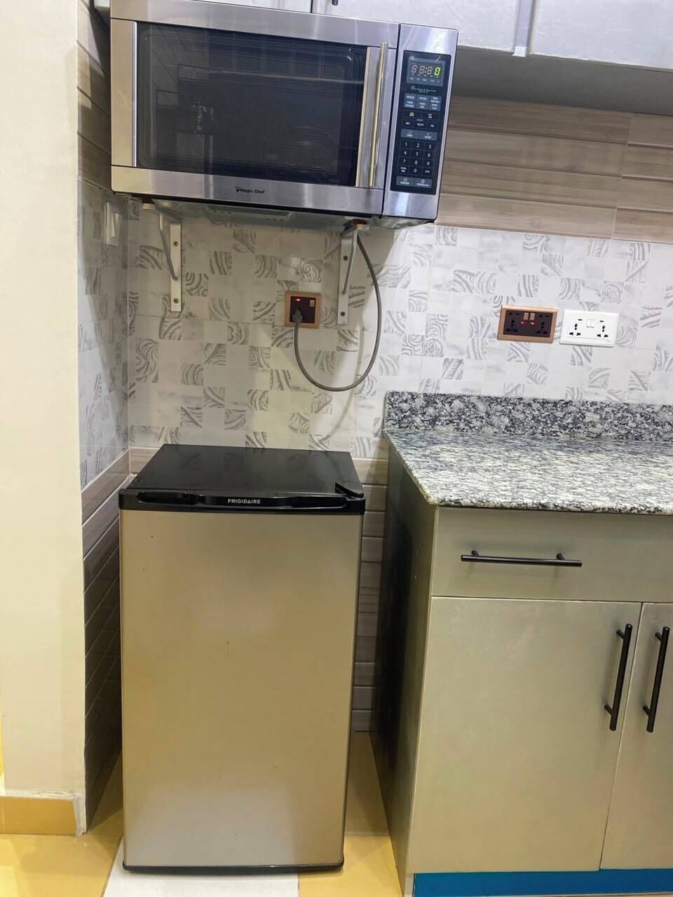 Una cocina con microondas, refrigerador y encimera.