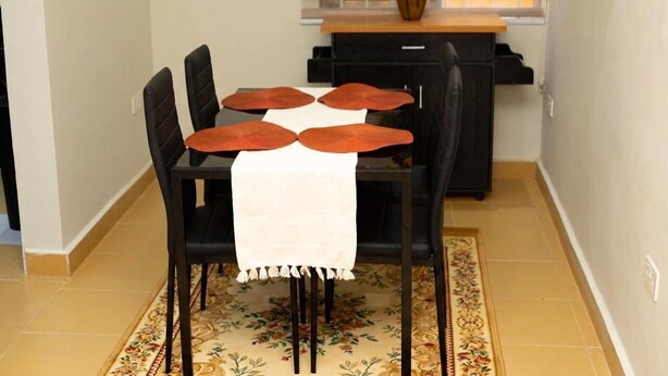 Een eetruimte met een tafel, stoelen en een vloerkleed.