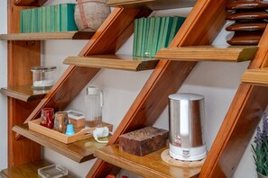 Ein Bücherregal aus Holz mit Büchern, einer Kaffeemaschine und Dekorationselementen.