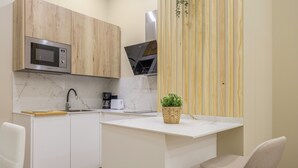 Eine moderne Küche mit Mikrowelle, Kaffeemaschine und einer kleinen Pflanze auf der Arbeitsfläche.