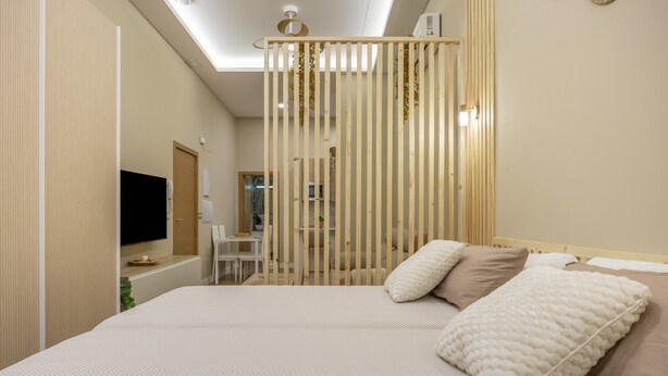 Ein modernes Hotelzimmer mit einem großen Bett, einem Fernseher, einem Schreibtisch und einer Deckenleuchte.