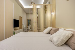 Una habitación de hotel moderna con una cama grande, un televisor, un escritorio y una lámpara de techo.