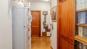 A hallway with wooden doors, a refrigerator, and a bookshelf with books. - Room 'La Chicca Di Francesca- Room 3' with Private Terrace, Wi-Fi and Air Conditioning (Santa Teresa Gallura)
