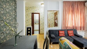 A living room with a sofa, a dining table, and a vase of flowers. - 'Juderia Center Premium Suites Free Parking' Apartment with Balcony, Wi-Fi & Air Conditioning (Seville)