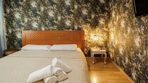 A neatly made bed with white linens and rolled towels, a wooden headboard, and a nightstand with a lamp. - 'Juderia Center Premium Suites Free Parking' Apartment with Balcony, Wi-Fi & Air Conditioning (Seville)