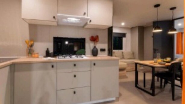 Una cocina moderna con una isla central, electrodomésticos integrados e iluminación colgante.