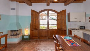 Una cocina rústica con vigas de madera, chimenea y comedor con mesa y sillas.