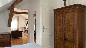 A bedroom with a wooden wardrobe, a bed with white bedding, and a wooden floor.