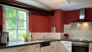 A modern kitchen with a window, stainless steel appliances, and wooden cabinets.