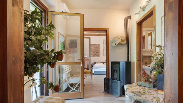 A hallway with a wooden bench, a fireplace, and a bed in the background. - Apartment Casa 'Bianca' with Wi-Fi and Air Conditioning (Novara)