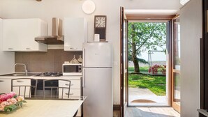 A modern kitchen with white cabinets, a stainless steel range hood, a refrigerator, and a dining area with a table and chairs. - Apartment Casa 'Bianca' with Wi-Fi and Air Conditioning (Novara)