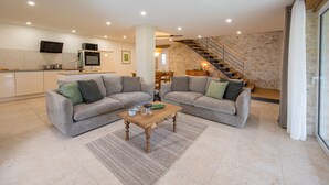 A modern living room with two sofas, a coffee table, and a kitchen in the background. - Holiday Home 'Gite Coeur Des Ondes - Tournesol' with Shared Terrace, Shared Garden and Wi-Fi (Saint-Georges)