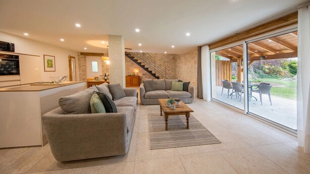 A modern living space with a kitchen, two sofas, a dining area, and a staircase leading to an outdoor patio. - Holiday Home 'Gite Coeur Des Ondes - Tournesol' with Shared Terrace, Shared Garden and Wi-Fi (Saint-Georges)