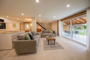 A modern living space with a kitchen, two sofas, a dining area, and a staircase leading to an outdoor patio. - Holiday Home 'Gite Coeur Des Ondes - Tournesol' with Shared Terrace, Shared Garden and Wi-Fi (Saint-Georges)