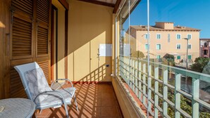 Un balcón con una silla, una mesa pequeña y vistas a edificios.