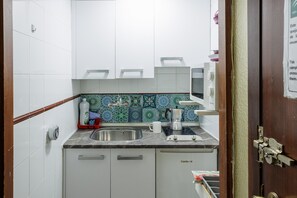 A compact kitchen with white cabinets, a stainless steel sink, a coffee maker, and a tiled backsplash. - 'Triana Centro Histórico' Apartment with Wi-Fi and Air Conditioning (Seville)
