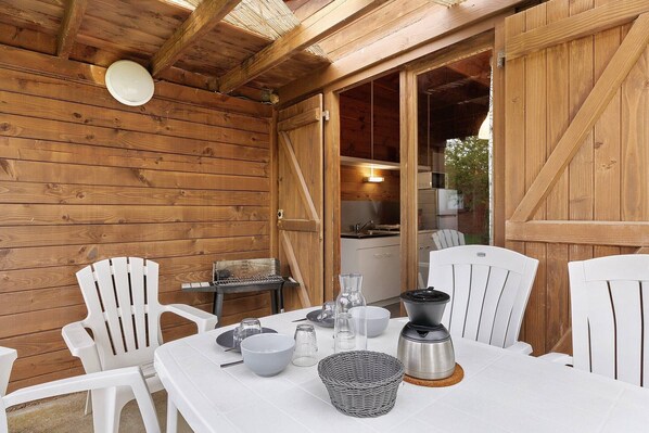 A wooden cabin with a dining table set for four, chairs, a coffee maker, and a basket.
