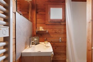 A wooden cabin bathroom with a white sink, a small window, and a towel rack.