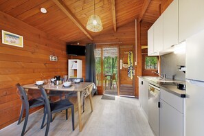 A wooden interior with a dining table, chairs, a kitchen area, and a view through a doorway. - Chalet “Prestige Le 13” with Shared Pool, Communal Garden and Wi-Fi (Saint-Gervais)