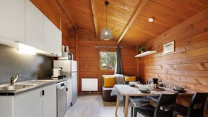 A compact kitchen with modern appliances, a dining area with a table and chairs, and a wooden interior. - Chalet “Prestige Le 13” with Shared Pool, Communal Garden and Wi-Fi (Saint-Gervais)