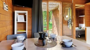 A wooden cabin interior with a dining table set, a television, and a view of the outdoors. - Chalet “Prestige Le 13” with Shared Pool, Communal Garden and Wi-Fi (Saint-Gervais)