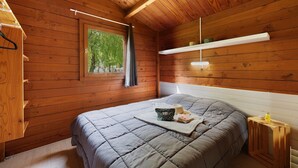 A wooden cabin bedroom with a bed, a window, and a shelf. - Chalet “Prestige Le 13” with Shared Pool, Communal Garden and Wi-Fi (Saint-Gervais)