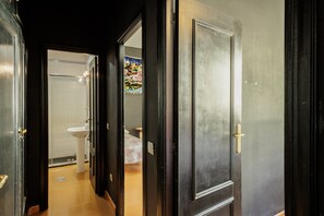 A hallway leading to a bathroom with a toilet, sink, and a shower.
