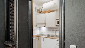 A kitchen with white cabinets, a stainless steel sink, and a tiled backsplash.