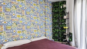 Un dormitorio con pared decorada, una cama con cubierta roja y una pared cubierta de plantas verdes.