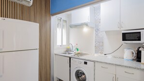 Una cocina compacta con lavadora, microondas y lavamanos.
